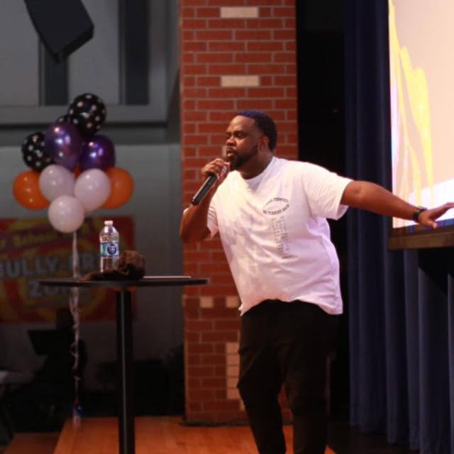 Kevin D. Money speaking at a school assembly